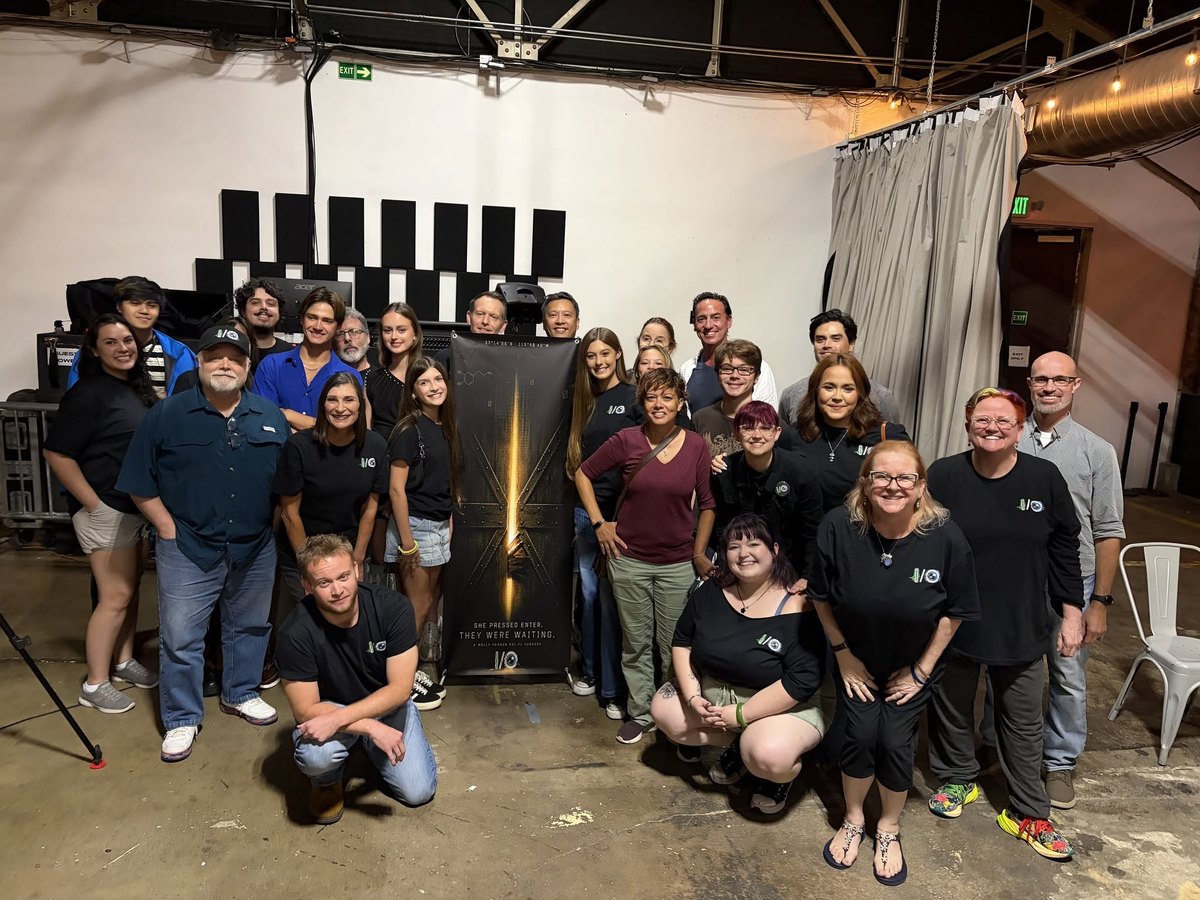 Large group photograph of I/O cast and crew with the threshold banner.